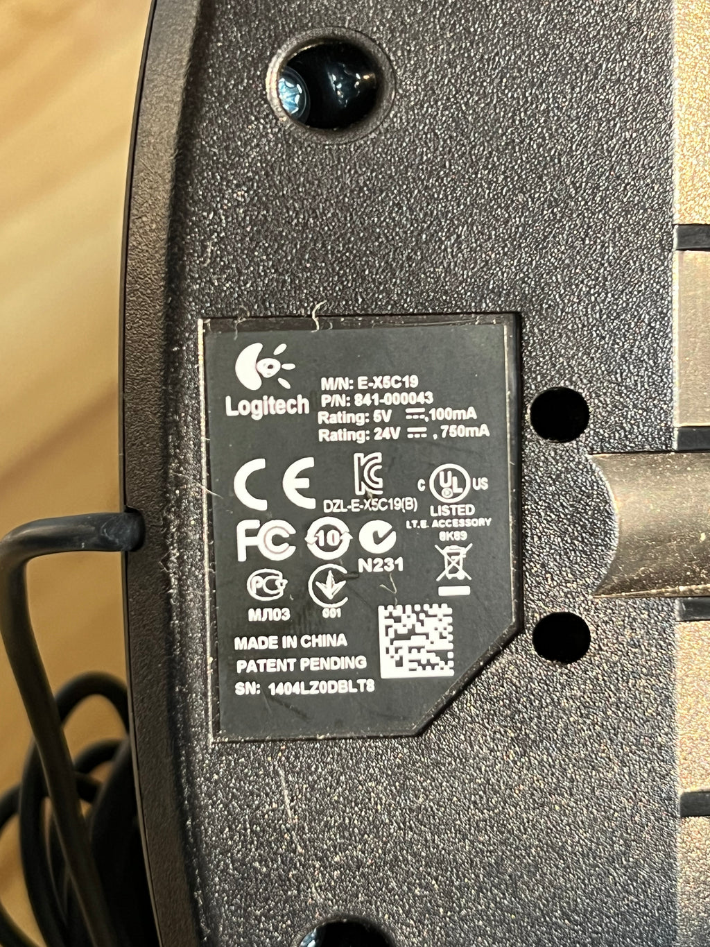 Close-up of a power adapter with certification labels on a beige background
